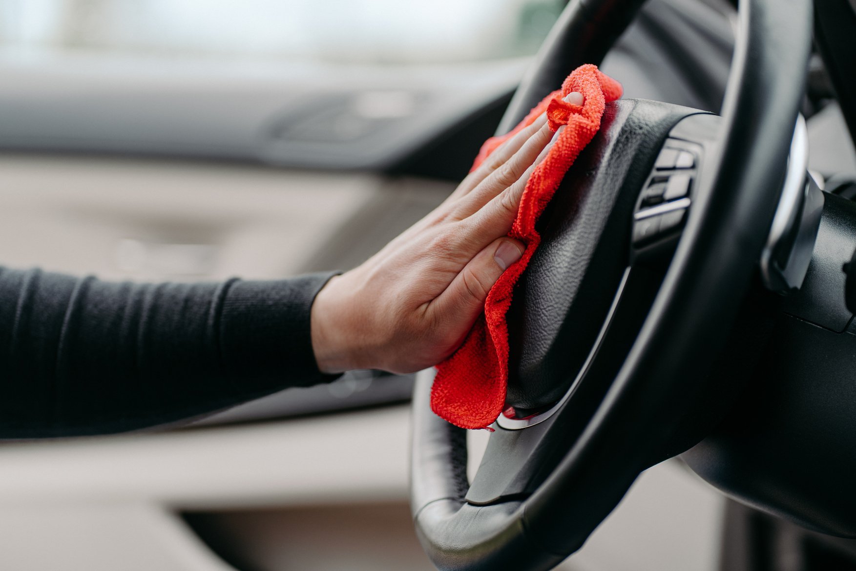 Mans Hand Cleaning Luxury Car Interior. Wiping Steering Wheel during Coronavirus. Washing Auto from inside. Hygiene Concept